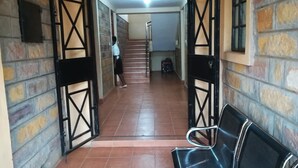 Un pasillo con suelo de baldosas, una persona caminando y un banco.