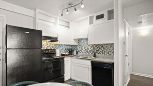 A modern kitchen with white cabinets, a black refrigerator, a stove, and a dishwasher. - Cozy Studio Walk to UT & Moody 7 Min to ACL (Austin)