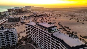 Un hotel de gran altura con varios pisos, una piscina en la azotea y vista al mar.
