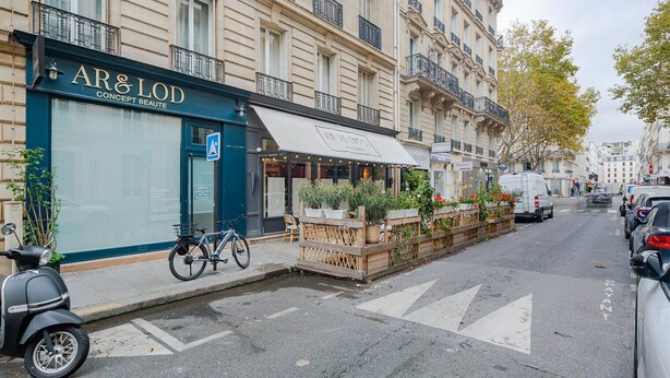 A street view with a cafe named 'AR & LOD Concept Beaute' on the left, a row of parked cars, and a white van on the right. - Blueground | Gros-Caillou, view, nr Eiffel Tower (Paris)