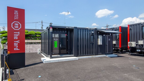 A compact hotel structure with a sign indicating 'HOTEL The Yard' and a visible entrance door. - Hotel R9 The Yard Ube (Ube)