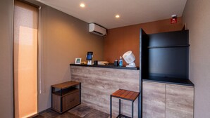 A modern bathroom with a wooden vanity, a small table, a wall-mounted fan, and a digital thermostat. - Hotel R9 The Yard Ube (Ube)