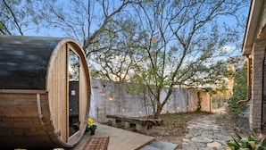 A wooden barrel-shaped room with a bench and potted plants outside.