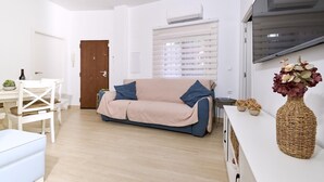Una sala de estar moderna con un sofá, una mesa de comedor y un televisor.