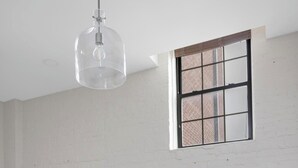 Ein Essbereich mit einem Marmortisch, Holzstühlen, einer Hängeleuchte und einem Fenster mit Gittermuster.
