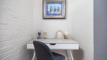 Un bureau blanc orné d’un tableau encadré, d’un globe terrestre et d’un ventilateur.