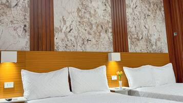 Een hotelkamer met een groot bed, een houten hoofdeinde, wanden met een marmerpatroon en twee bedlampen.