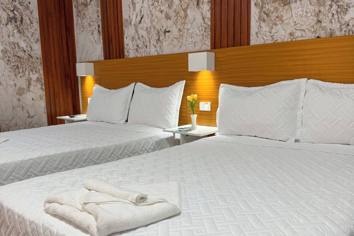 A hotel room with a large bed, two bedside tables, and a wooden headboard.