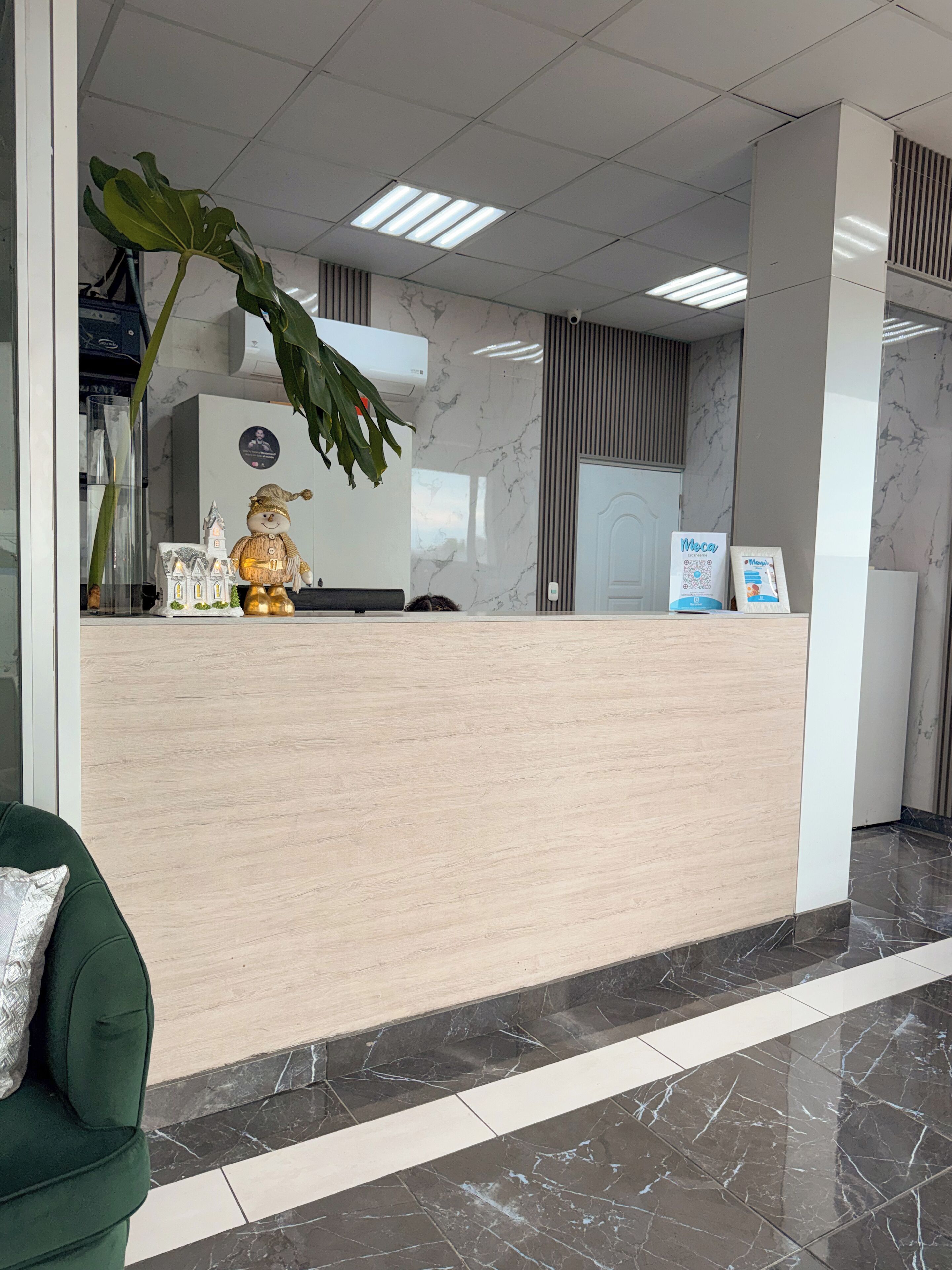 A reception desk with a marble floor, a green sofa, and a decorative plant.