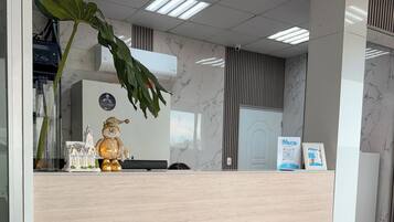 A reception desk with a marble floor, a green sofa, and a decorative plant.