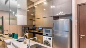 Una cocina moderna con electrodomésticos de acero inoxidable, lavadora integrada y una isla grande con pileta.