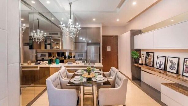 Un comedor moderno con una mesa de vidrio, sillas blancas tapizadas y una araña.