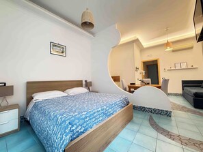 A hotel room with a bed, bedside table, lamp, and a mirror. - Casa Evelina (Sant'Agnello)