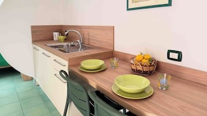 Uma cozinha compacta com pia, bancada de madeira e um espaço de refeições com cadeiras.