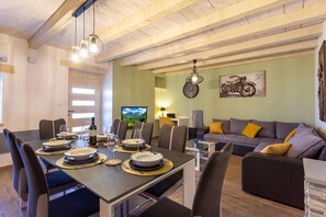 Un comedor con una mesa dispuesta para cuatro, un sofá y un reloj de pared.