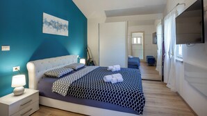 A bedroom with a bed, bedside table, lamp, and artwork on the wall.