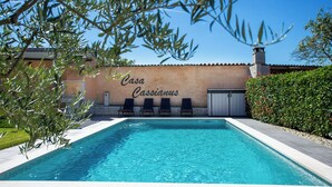 A swimming pool with a wall labeled "Casa Cassianas" and a row of lounge chairs.