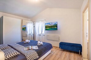 A bedroom with a bed, a bench, a TV, and a mirror.