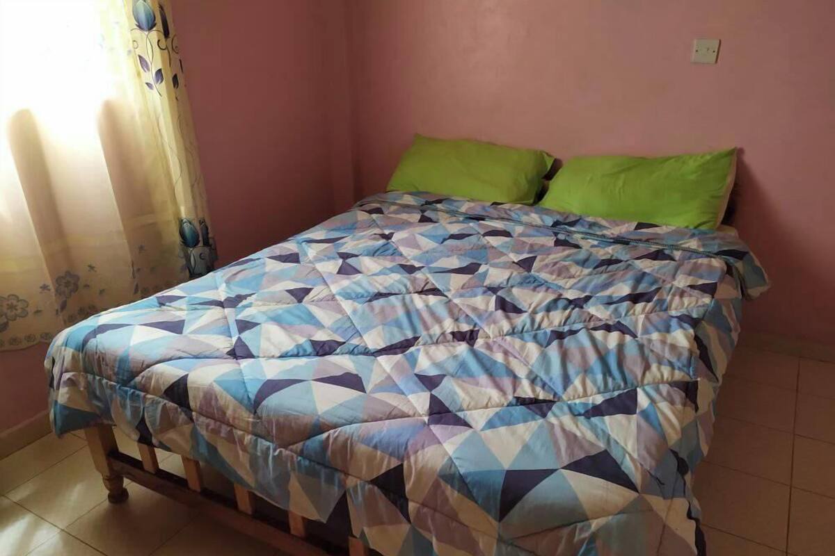 A bedroom with a bed, a green pillow, and a patterned bedspread.