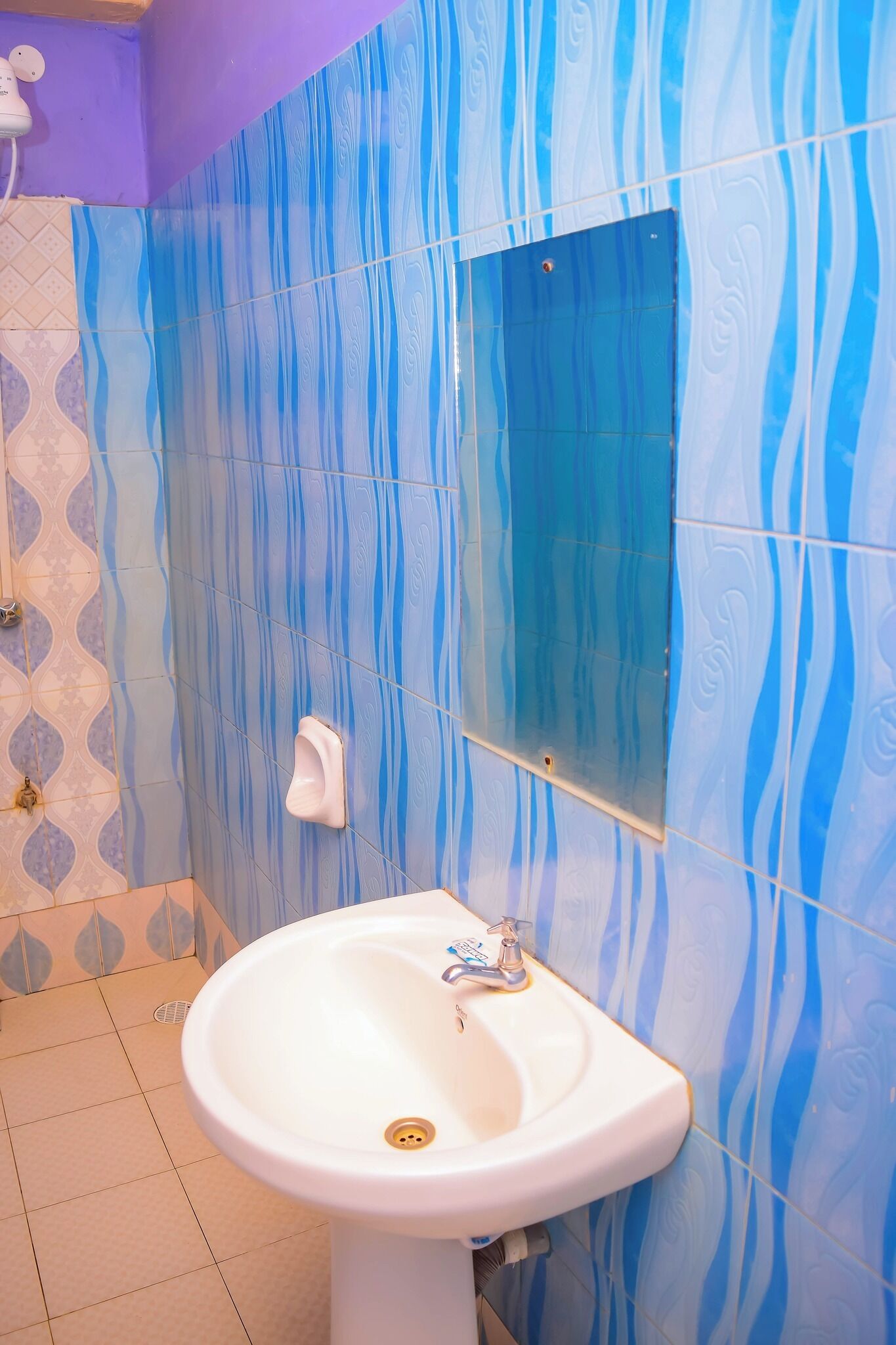 Een badkamer met een witte wastafel, blauw betegelde muren en een kleine spiegel.