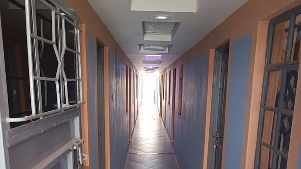 Un long couloir étroit, doté d’un sol carrelé et orné d’un motif géométrique au centre.