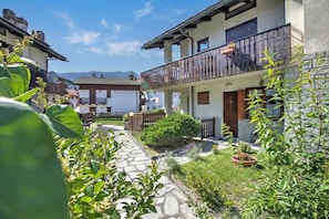 A courtyard with stone pathways, potted plants, and a building with a balcony.
