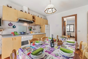 A kitchen with wooden cabinets, a stove, and a dining table set with plates and a bottle.