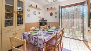 A dining area with a table set for four, wooden chairs, a cabinet with glass doors, and a decorative ceiling light. - Maison Rosamunda for 6 with Garden, Oulx, Italy (Oulx)
