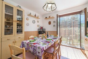 A dining area with a table set for four, wooden chairs, a cabinet with glass doors, and a decorative ceiling light.