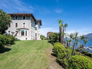 A large, multi-story building with a well-maintained lawn and a view of the sea.