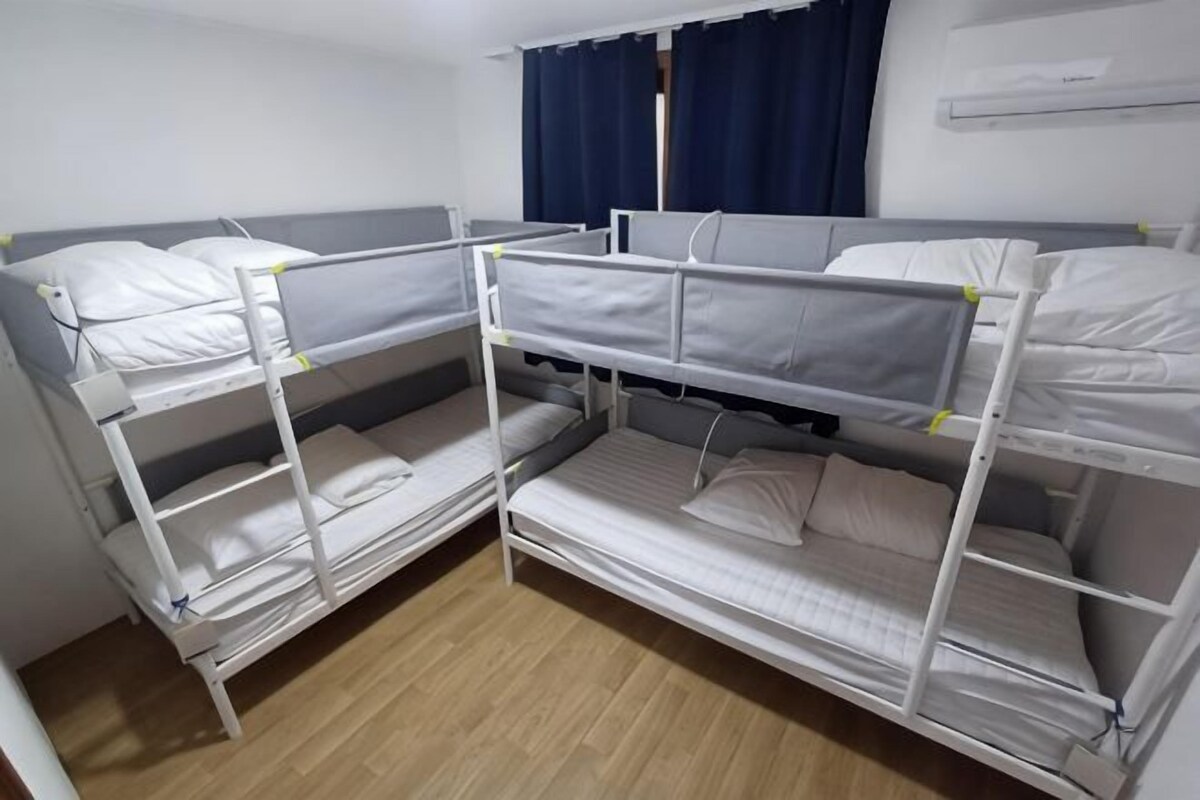 A bunk bed room with a window, curtains, and an air conditioning unit.