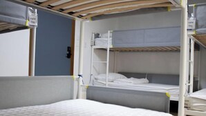 A bunk bed room with a headboard, a ladder, and a door. - Ocean's Guesthouse (Seoul)