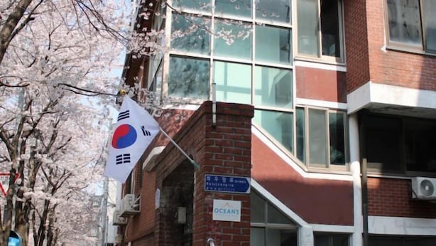 A building with a red brick facade, large windows, and a sign for 'OCEANS'. - Ocean's Guesthouse (Seoul)