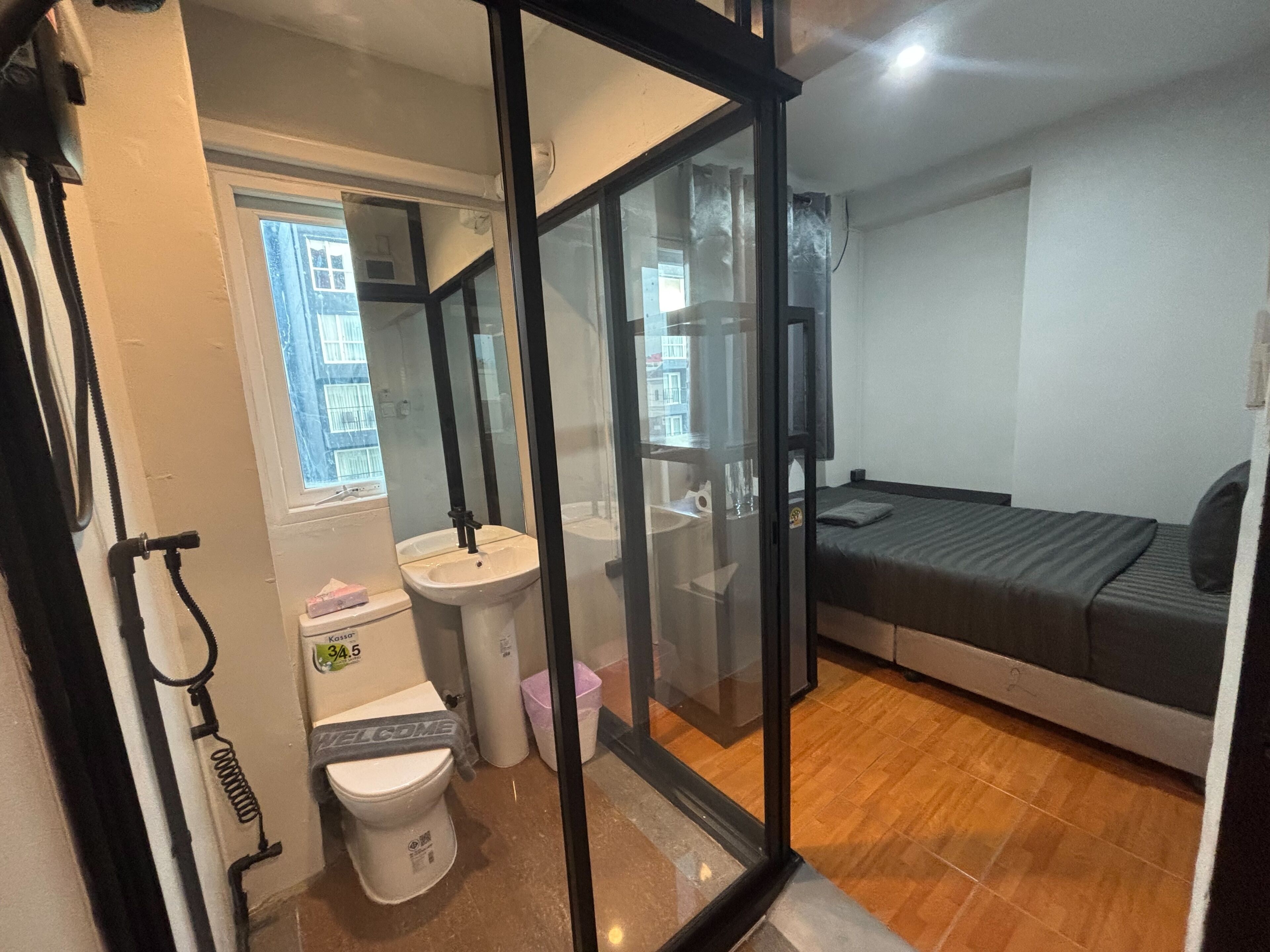 A small, modern room with a bed, a sink, and a toilet.