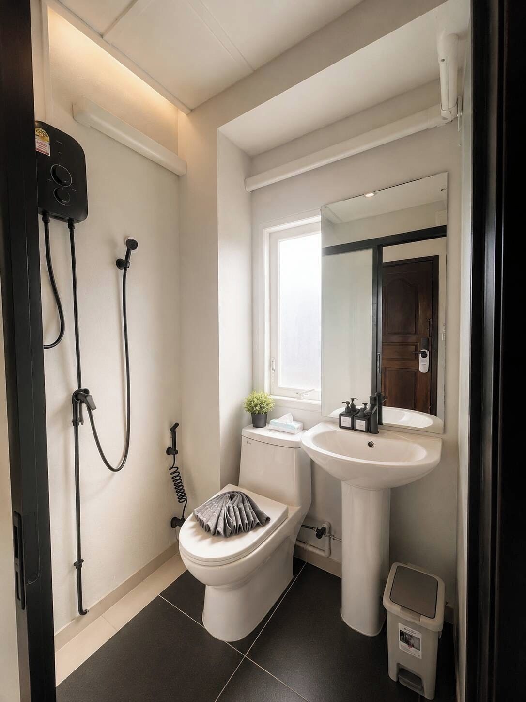A modern bathroom with a toilet, bidet, sink, and shower.