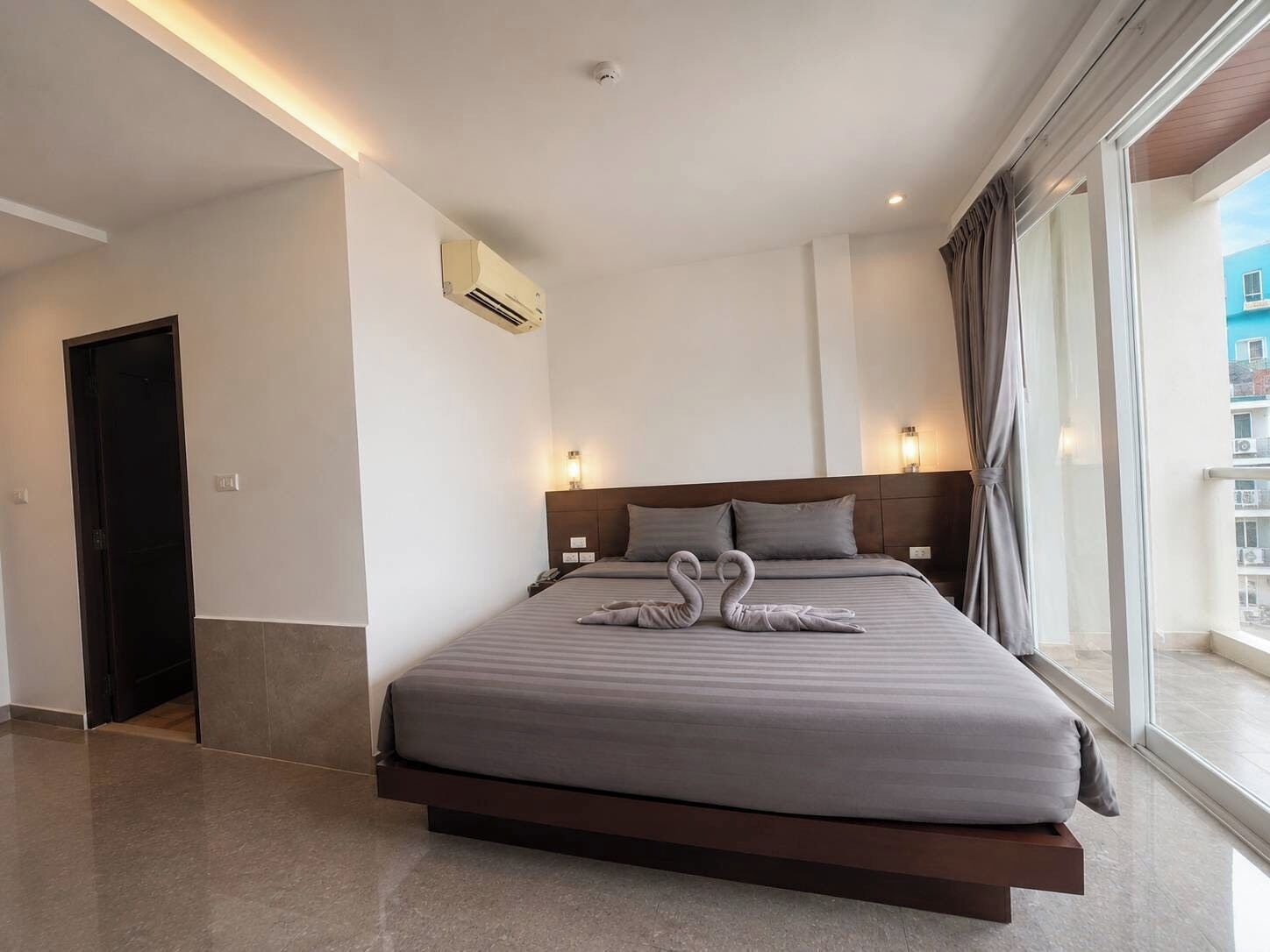 Een moderne hotelkamer met een groot bed, uitzicht op de stad en een balkon.