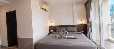 A modern hotel room with a large bed, a view of the city, and a balcony.