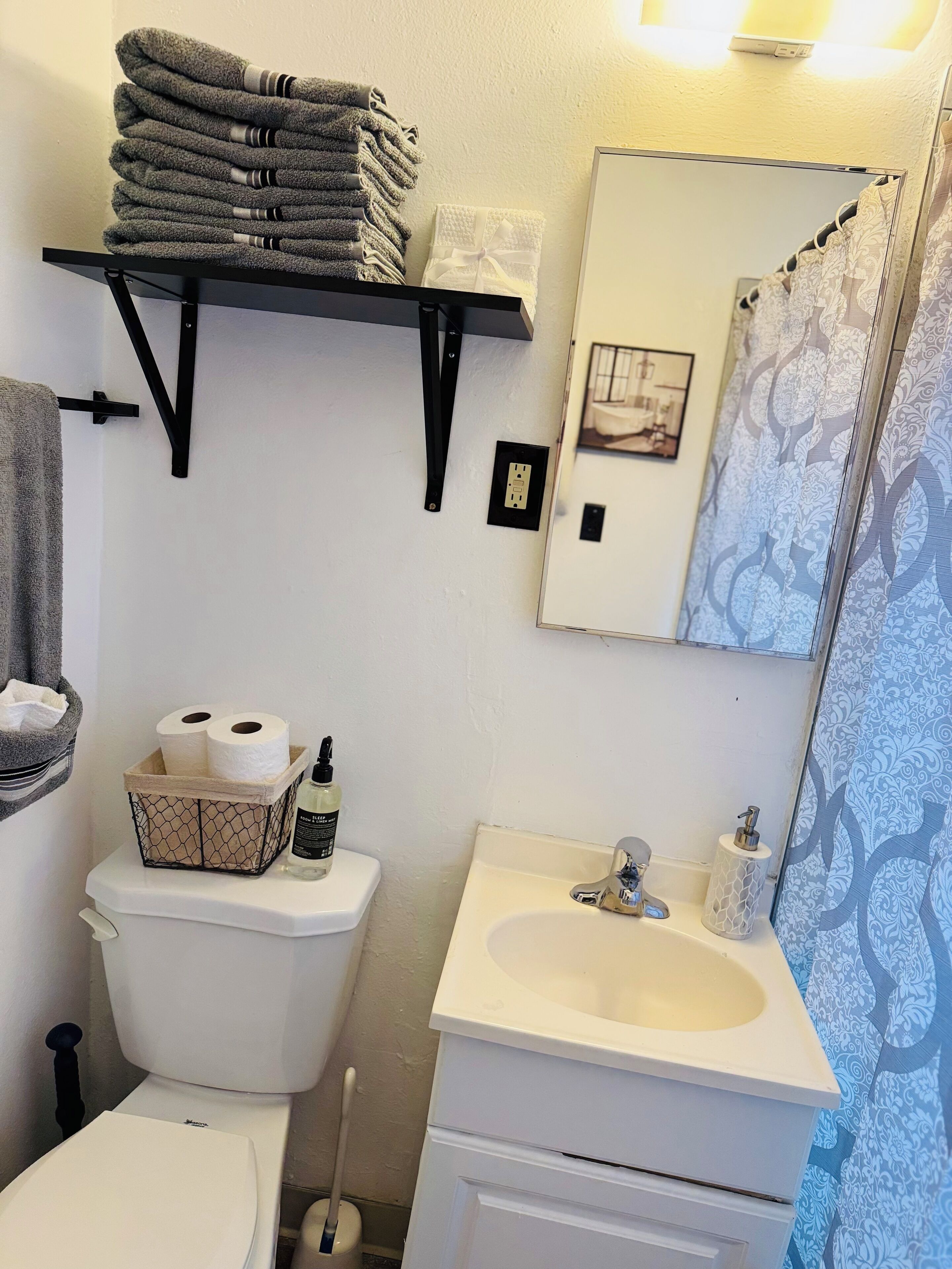 Un bagno con il water, un lavandino e un portaservizi con asciugamani piegati.