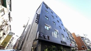 Un hôtel moderne, reconnaissable à son imposante enseigne « HÔTEL » placée à l’entrée.