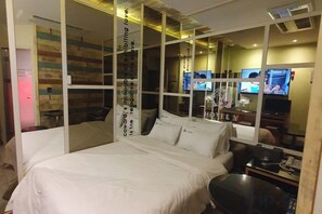 Een slaapkamer met een bed, een televisie en een bureau met een computer.