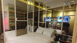 Une chambre d’hôtel avec un lit, une petite table et deux téléviseurs.