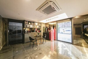 A modern hotel lobby with a dining area, a reception desk, and a view of the street. - Eunpyeong Y Hotel (Seoul)