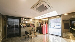 Un hall d’hôtel moderne comprenant un espace repas, un comptoir d’accueil et une vue sur la rue à travers les portes vitrées.