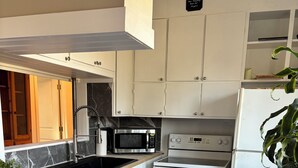 A modern kitchen with white cabinetry, a stainless steel microwave, a built-in oven, and a refrigerator.
