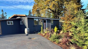 A single-story building with a garage, surrounded by a variety of plants and trees.