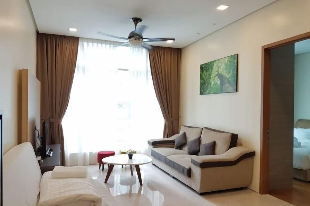 Un salon moderne avec un canapé, une table basse, un ventilateur de plafond et un tableau accroché au mur.