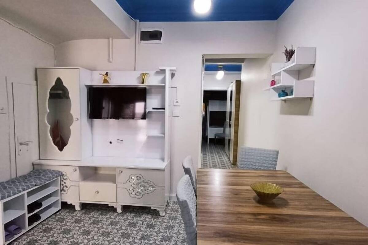 A room with a bed, a TV, a wardrobe, a desk, and a dining table.