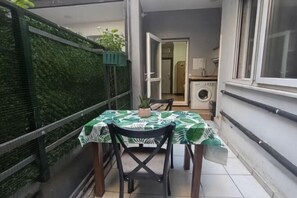 Un balcon avec une table et des chaises, un lave-linge et un mur végétal.