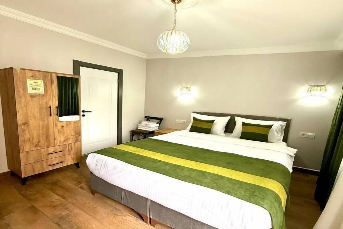 A bedroom with a bed, a wooden wardrobe, a nightstand, and two wall-mounted lights.