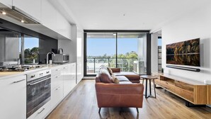 A modern kitchen with a large window, a sofa, and a TV. - Pristine 1-bed Apartment Near Local Cafes (Melbourne)
